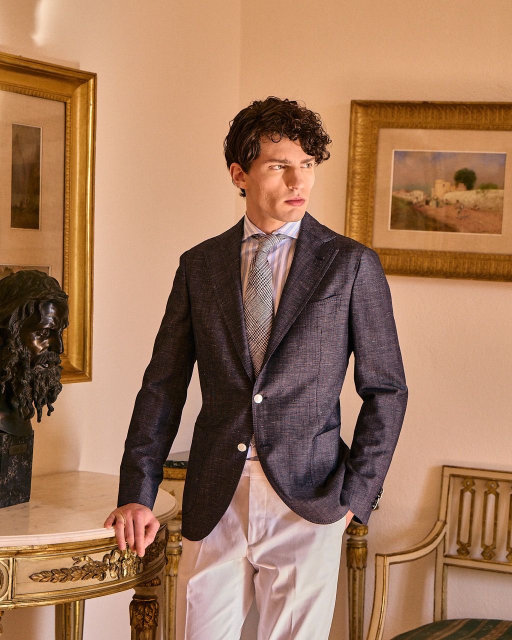 a mid-waist portrait of a well-dressed man in an antique home posing casually